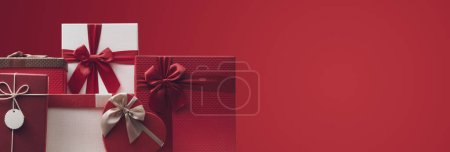 Téléchargez les photos : Beaux cadeaux de Noël sur fond rouge, vacances et concept de célébration - en image libre de droit