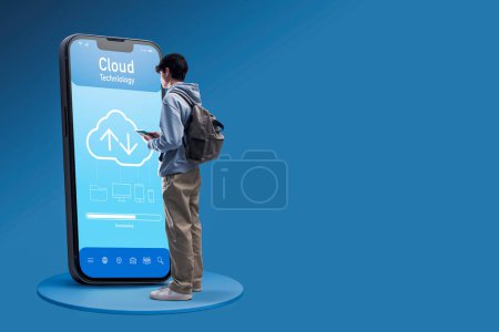 Téléchargez les photos : Adolescent utilisant une application cloud sur un grand smartphone, concept de stockage et de sécurité des données, espace de copie - en image libre de droit