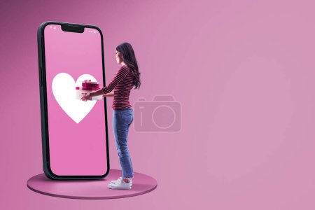 Téléchargez les photos : Femme heureuse faisant des achats en ligne sur un grand smartphone avec cœur et recevoir des cadeaux, copier l'espace - en image libre de droit
