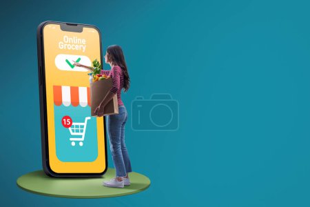 Téléchargez les photos : Femme tenant un sac d'épicerie et faisant des courses en ligne, elle commande des produits sur l'application mobile - en image libre de droit
