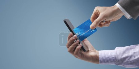 Foto de Empresario que toma una tarjeta de crédito desde el smartphone de un usuario, concepto de ciberseguridad y phishing - Imagen libre de derechos
