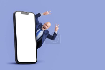 Téléchargez les photos : Homme d'affaires prospère célébrant avec les bras levés et grand smartphone avec écran blanc, marketing et concept d'entreprise - en image libre de droit