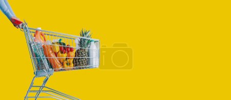 Téléchargez les photos : Femme poussant un panier de supermarché plein d'épicerie, concept de commerce et de détail, espace de copie - en image libre de droit