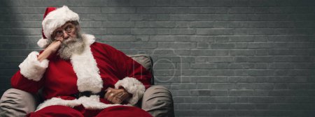 Foto de Lazy cansado Santa Claus esperando la Navidad, él está sentado en el sillón en casa y descansando la cabeza en la mano - Imagen libre de derechos