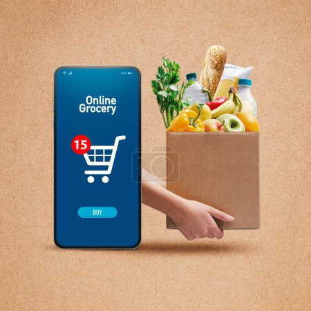 Foto de Manos sosteniendo una caja llena de alimentos frescos y aplicación de compras en línea en el teléfono inteligente - Imagen libre de derechos