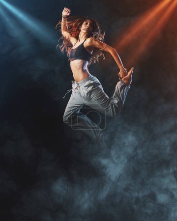 Foto de Bailarina profesional que actúa en el escenario, salta rodeada de humo, danza y concepto de entretenimiento - Imagen libre de derechos