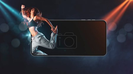 Foto de Bailarina profesional saltando desde una pantalla de teléfono inteligente y luces de escenario en el fondo: concepto de entretenimiento y aplicaciones - Imagen libre de derechos