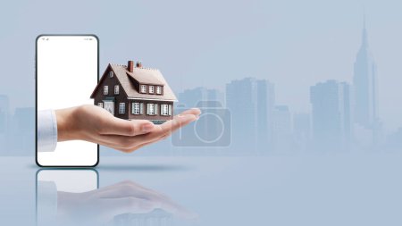 Téléchargez les photos : Real estate agent hand showing a model house in a smartphone screen, real estate app concept, copy space - en image libre de droit