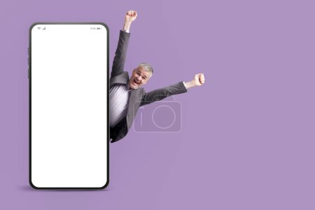Téléchargez les photos : Homme d'affaires prospère célébrant avec les bras levés et grand smartphone avec écran blanc, marketing et concept d'entreprise - en image libre de droit