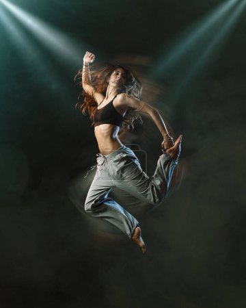 Téléchargez les photos : Danseuse professionnelle sur scène, elle saute entourée de fumée, de danse et de concept de divertissement - en image libre de droit