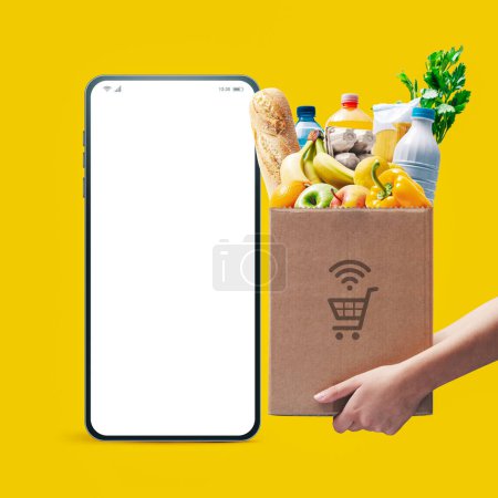 Téléchargez les photos : Smartphone avec écran vierge et femme tenant une boîte pleine d'épicerie, concept d'épicerie en ligne - en image libre de droit