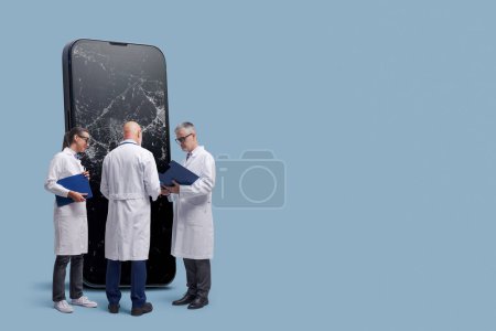 Photo for Smartphone and electronics repair service concept: team of technician doctors and big mobile phone with broken screen, blank copy space - Royalty Free Image