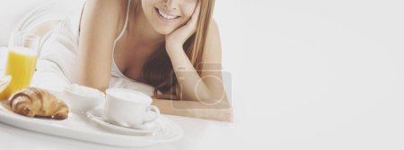 Photo for Smiling woman lying on bed and having breakfast, healthy lifestyle concept, banner with copy space - Royalty Free Image