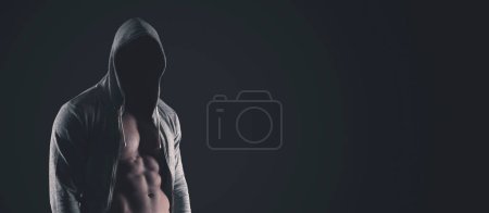 Photo for Handsome mysterious muscular man posing in the dark, he is wearing a hoodie and his face is hidden - Royalty Free Image