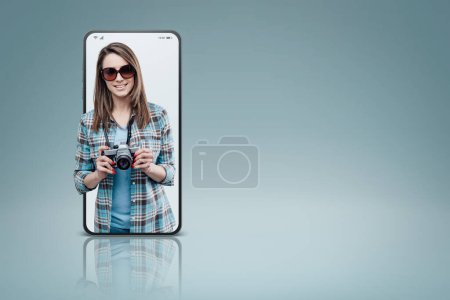 Photo for Smiling female photographer and tourist in a smartphone videocall and smiling, online  service concept - Royalty Free Image