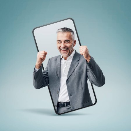 Foto de Cheerful successful businessman in a smartphone videocall and smiling, online  service concept - Imagen libre de derechos
