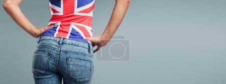 Téléchargez les photos : Belle adolescente vue de dos, elle porte un débardeur drapeau britannique et un jean - en image libre de droit