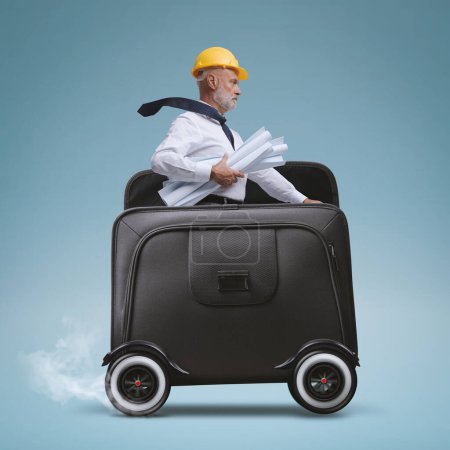 Téléchargez les photos : Professional architect riding a briefcase with wheels and reaching a construction site - en image libre de droit