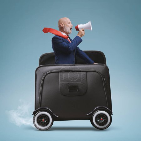 Téléchargez les photos : Businessman with megaphone riding a briefcase with wheels and shouting - en image libre de droit