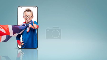 Téléchargez les photos : Smiling cute superhero thumbs up in a smartphone videocall and smiling, online  success concept - en image libre de droit