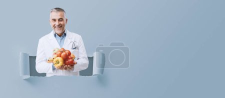 Foto de Nutricionista sonriente sosteniendo verduras y frutas frescas: concepto de salud y dieta vegetariana saludable - Imagen libre de derechos