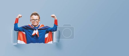 Photo for Cute smiling superhero showing off muscles, he is wearing a Union Jack flag as a cape - Royalty Free Image