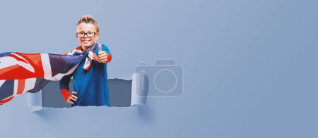 Photo for Smiling cute superhero thumbs up, he is wearing a British flag as a cape - Royalty Free Image
