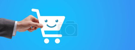 Téléchargez les photos : Homme d'affaires tenant une icône de panier souriant, concept d'achat en ligne - en image libre de droit