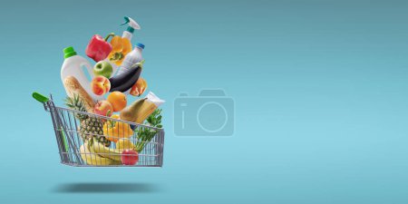 Téléchargez les photos : Fresh groceries and goods falling in a supermarket trolley, grocery shopping concept - en image libre de droit