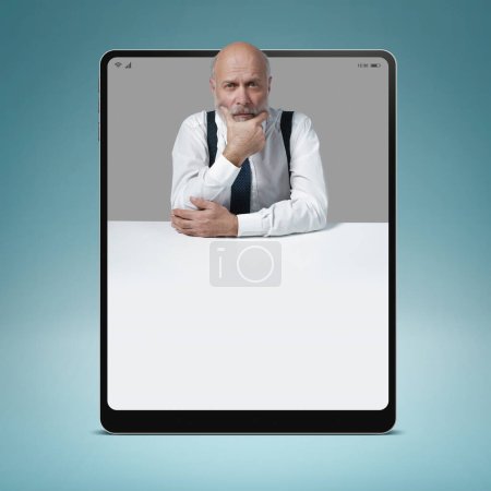 Téléchargez les photos : Homme d'affaires pensif dans une tablette numérique, il pense avec la main sur le menton, espace de copie vierge, concept de solution d'affaires - en image libre de droit