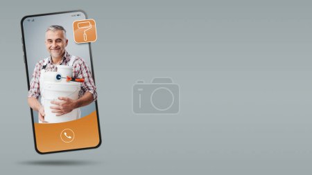 Téléchargez les photos : Peintre professionnel videocalling sur l'écran du smartphone, louer un contacteur en ligne - en image libre de droit