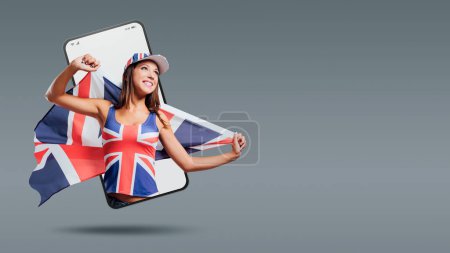 Foto de Alegre linda chica británica sosteniendo una bandera en un videocall smartphone y sonriendo - Imagen libre de derechos