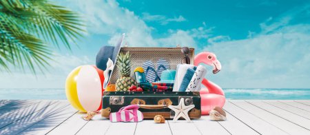 Photo for Vintage suitcase with colorful summer accessories at the tropical beach on the deck, summer vacations concept, copy space - Royalty Free Image