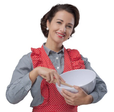 Foto de Cocinero vintage femenino mezclando ingredientes en un tazón y sonriendo - Imagen libre de derechos
