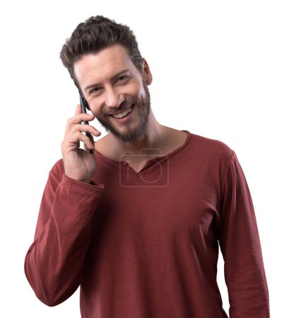 Foto de Joven sonriente hombre alegre teniendo una llamada telefónica y mirando a la cámara en el fondo blanco - Imagen libre de derechos