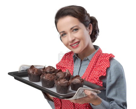 Photo for Smiling vintage woman holding a baking tray with chocolate home made muffins - Royalty Free Image