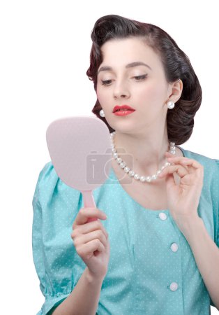 Photo for Elegant vintage style woman looking at herself in the mirror, she is checking her look - Royalty Free Image