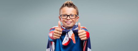 Photo for Smiling cute superhero thumbs up, he is wearing a British flag as a cape - Royalty Free Image