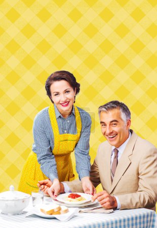 Téléchargez les photos : Vintage femme souriante servant des pâtes pour le déjeuner à son mari heureux - en image libre de droit