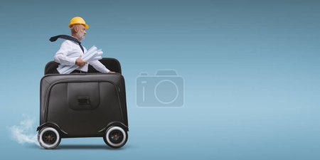 Téléchargez les photos : Professional architect riding a briefcase with wheels and reaching a construction site - en image libre de droit