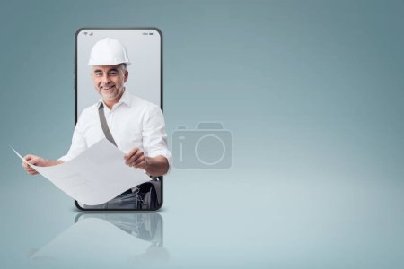 Photo for Professional architect checking a house blueprint in a smartphone videocall and smiling, online  service concept - Royalty Free Image