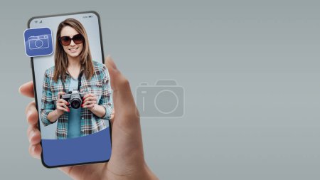 Foto de Fotógrafo sosteniendo una cámara en la pantalla del teléfono inteligente, concepto de servicios profesionales en línea - Imagen libre de derechos