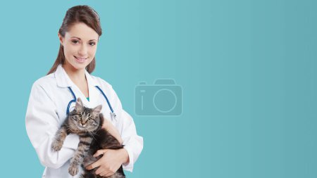 Photo for Veterinarian medical service: smiling female vet holding a cute cat, banner with copy space - Royalty Free Image