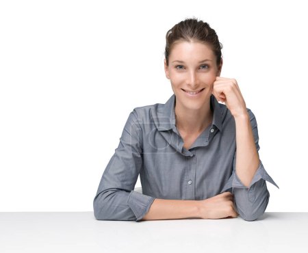 Foto de Mujer de negocios serena y segura sentada en el escritorio y posando, ella sonríe a la cámara - Imagen libre de derechos