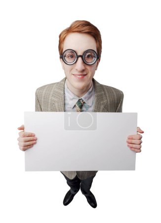 Foto de Divertido chico nerd con gafas gruesas, él está sosteniendo un signo en blanco y sonriendo - Imagen libre de derechos