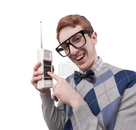 Photo for Funny nerd guy with big glasses holding a cordless phone and pushing a button - Royalty Free Image