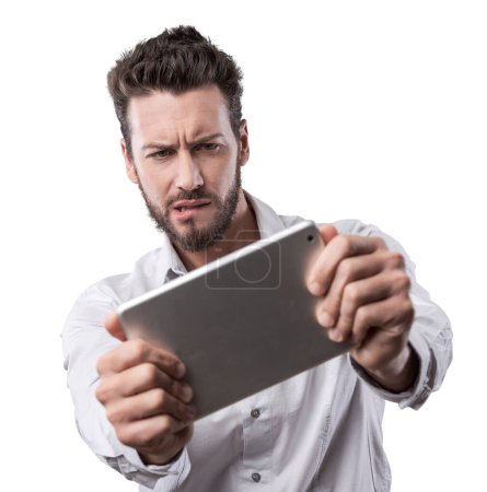 Téléchargez les photos : Homme confus mordre sa lèvre et regarder une tablette numérique - en image libre de droit