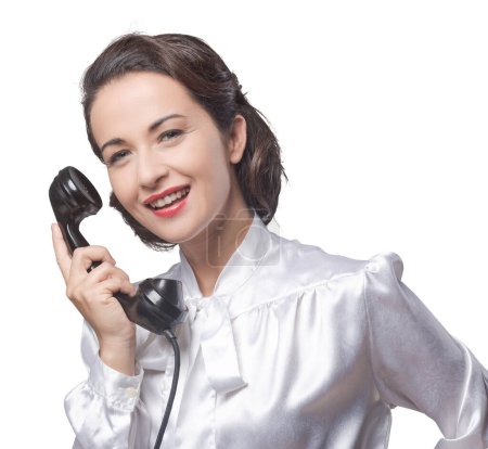 Téléchargez les photos : Attrayant vintage secrétaire sur le téléphone souriant à la caméra - en image libre de droit