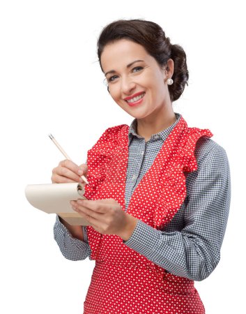 Photo for Smiling vintage housewife writing down a recipe ingredients on a notepad - Royalty Free Image