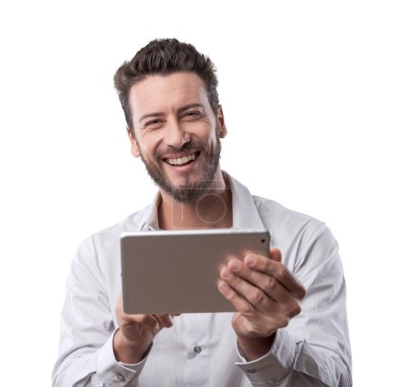 Téléchargez les photos : Homme confiant et souriant utilisant une tablette numérique et regardant la caméra - en image libre de droit